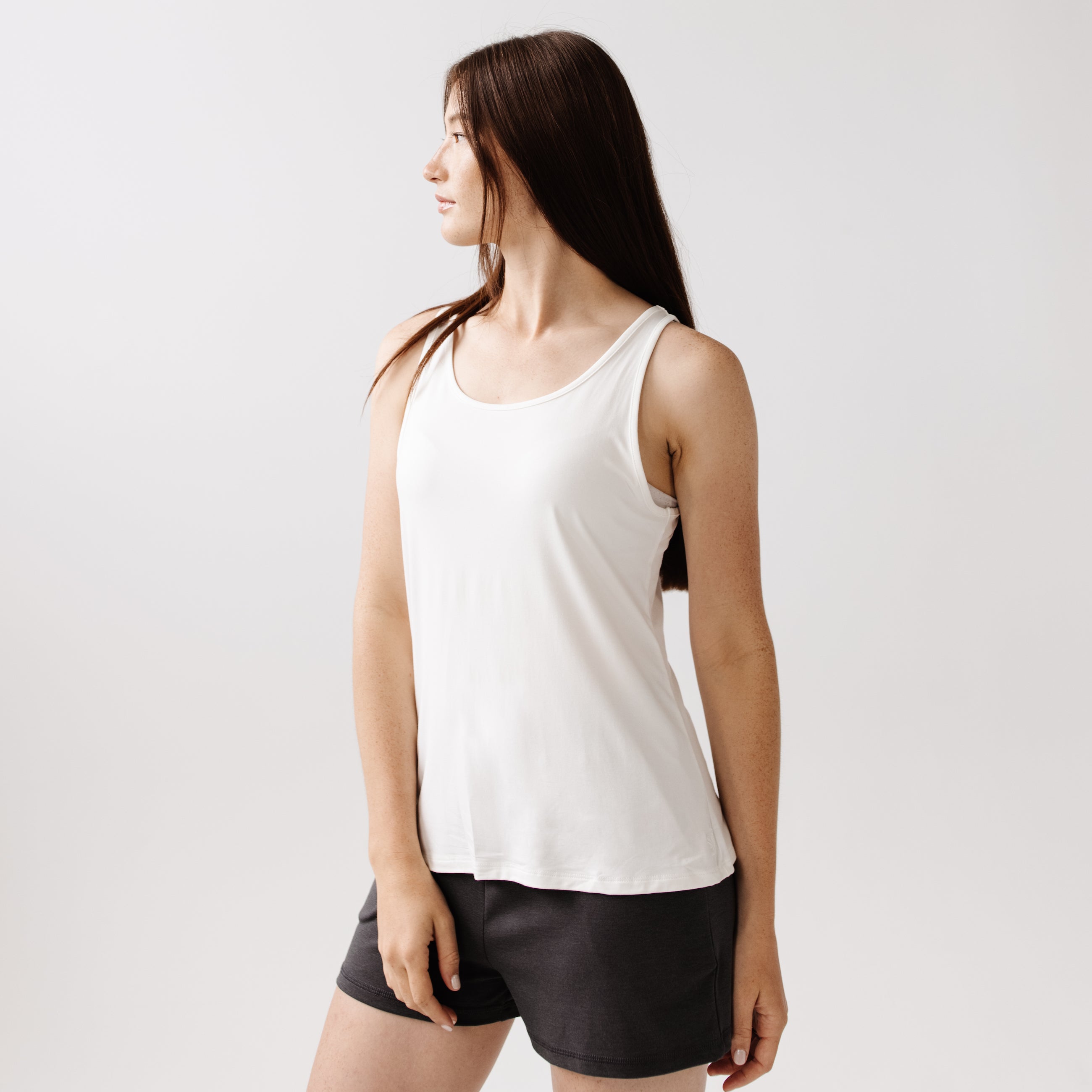 A woman facing backwards wears a white Cozy Earth Stretch Knit Tank |Color:Ivory